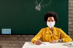 African American teacher with protective face mask holding a class at the school. Copy space.