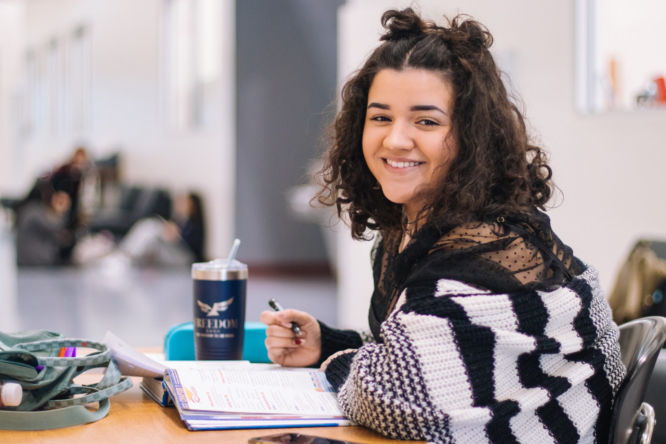 student smiling at desk with notebook